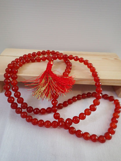 Red Agate Mala 108+1 beads with red and gold tassel on wooden stand