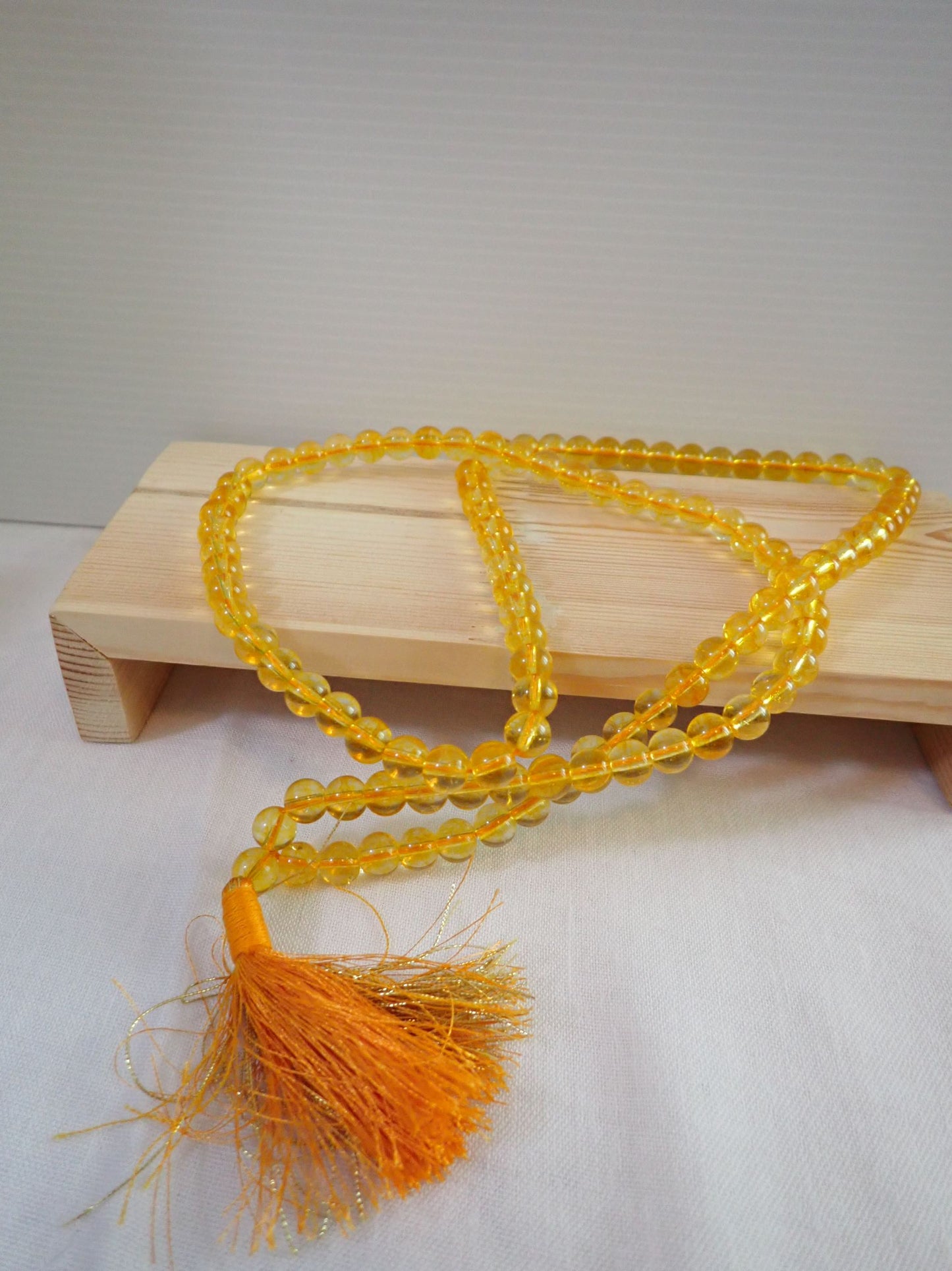 Citrine Mala 108+1 beads with orange tassel on wooden stand
