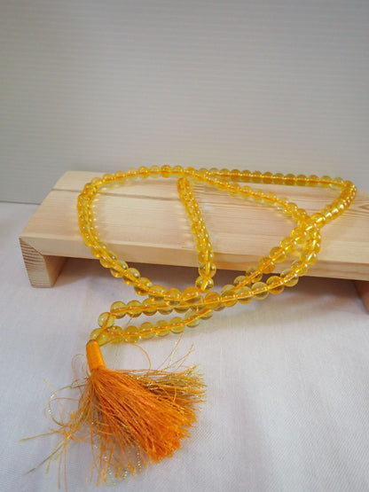 Citrine Mala 108+1 beads with orange tassel on wooden stand